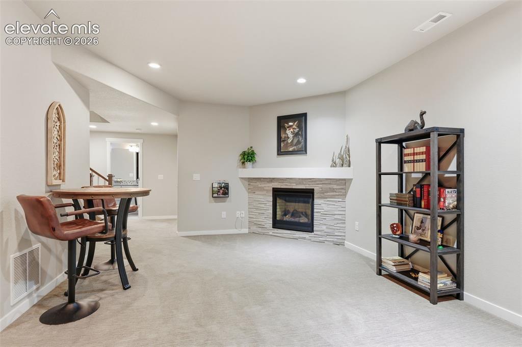 Image 24 of 43: A fireplace with a stacked stone facade and mantel, recessed lighting.