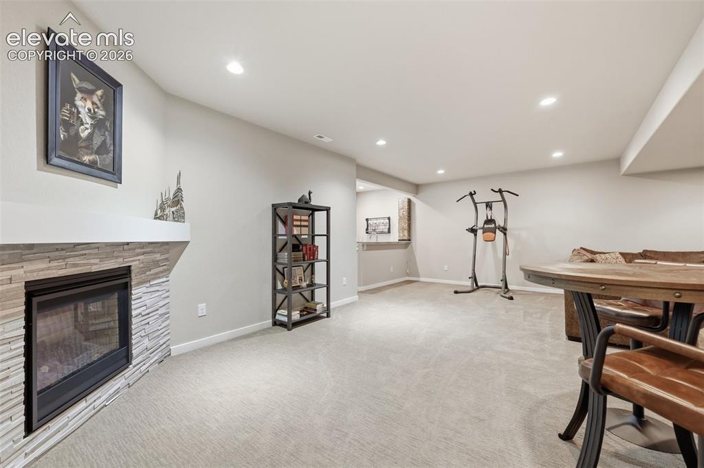Image 25 of 43: A fireplace with a stacked stone facade and mantel, recessed lighting.
