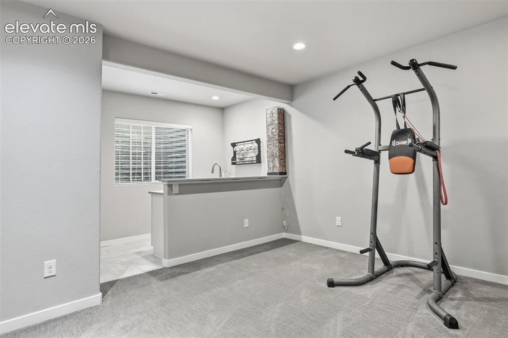 Image 27 of 43: Recessed lighting, wall-to-wall carpeting, and a built-in wet bar with a si