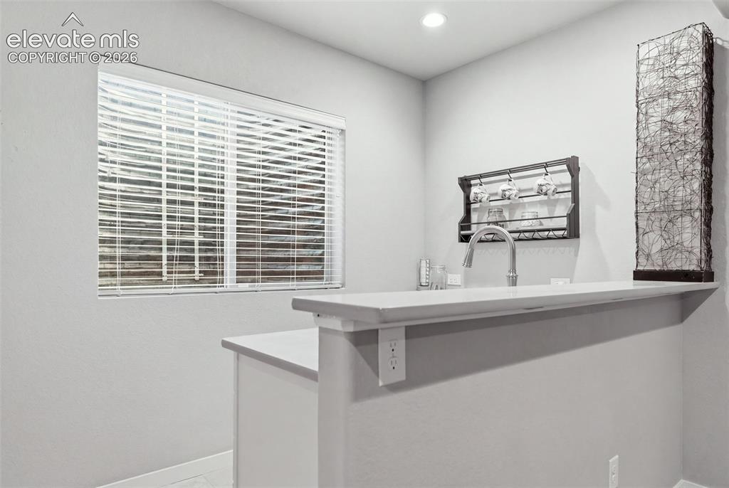 Image 28 of 43: Built-in counter with a stainless steel faucet, wall-mounted cup rack, and 
