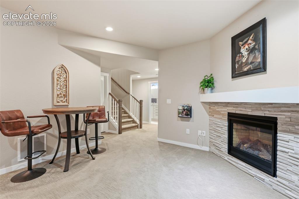 Image 29 of 43: A fireplace with a stacked stone facade and mantel, recessed lighting.