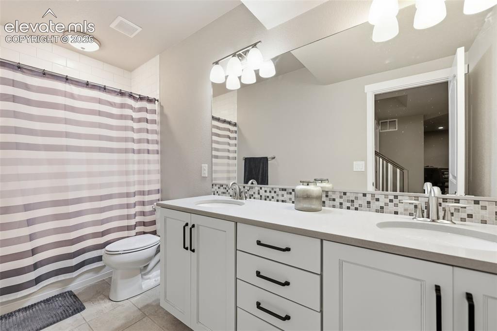 Image 32 of 43: Double vanity with undermount sinks, light stone countertops, and white cab