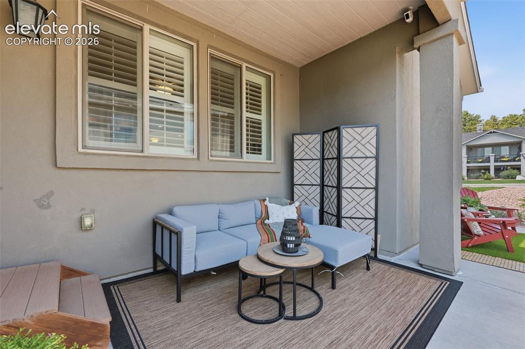 Image 33 of 43: Covered outdoor patio with a stucco exterior and white window shutters.