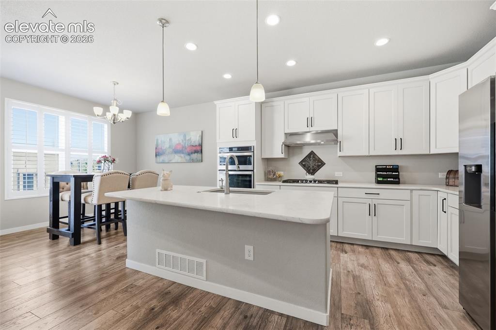 Image 4 of 43: Spacious kitchen with a central island, light color stone countertops, whit