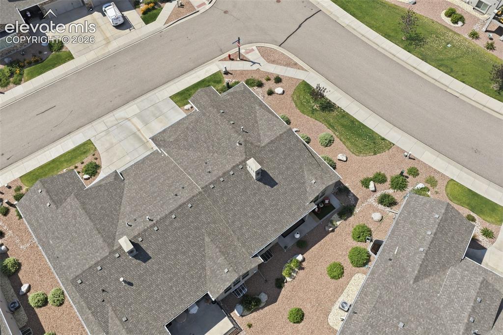 Image 40 of 43: Gray shingle roofing, paved driveway, landscaped yard with crushed rock and