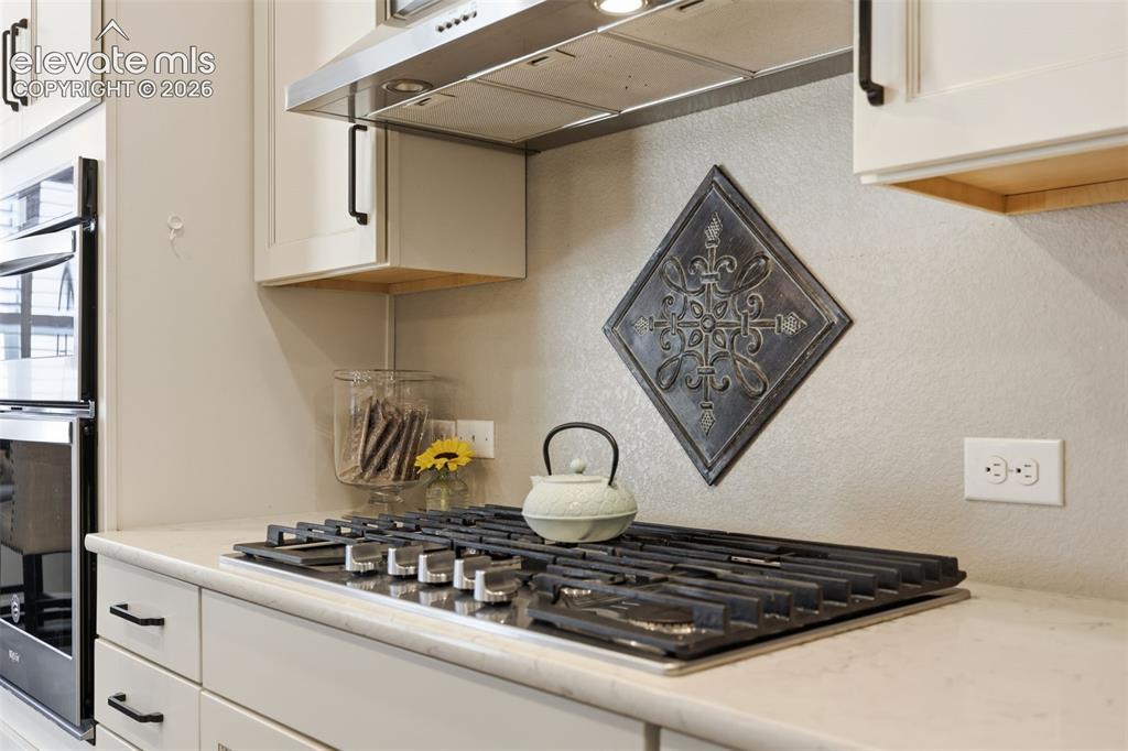 Image 6 of 43: White shaker cabinetry with black hardware, stainless steal gas cook top, s