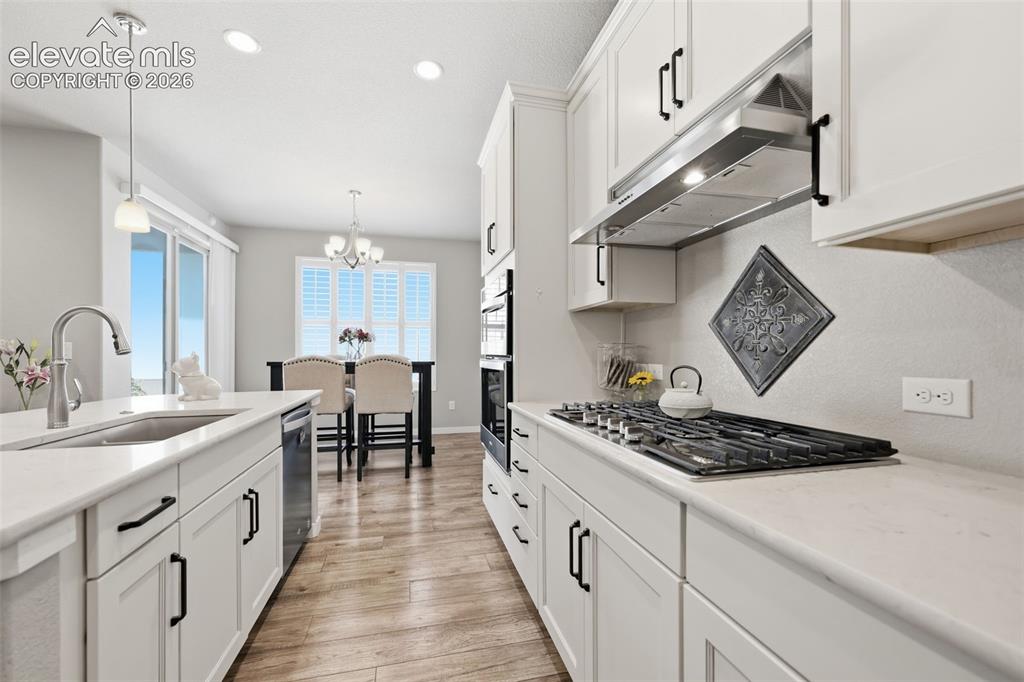 Image 7 of 43: White shaker cabinetry with black hardware, light brown luxury vinyl plank 
