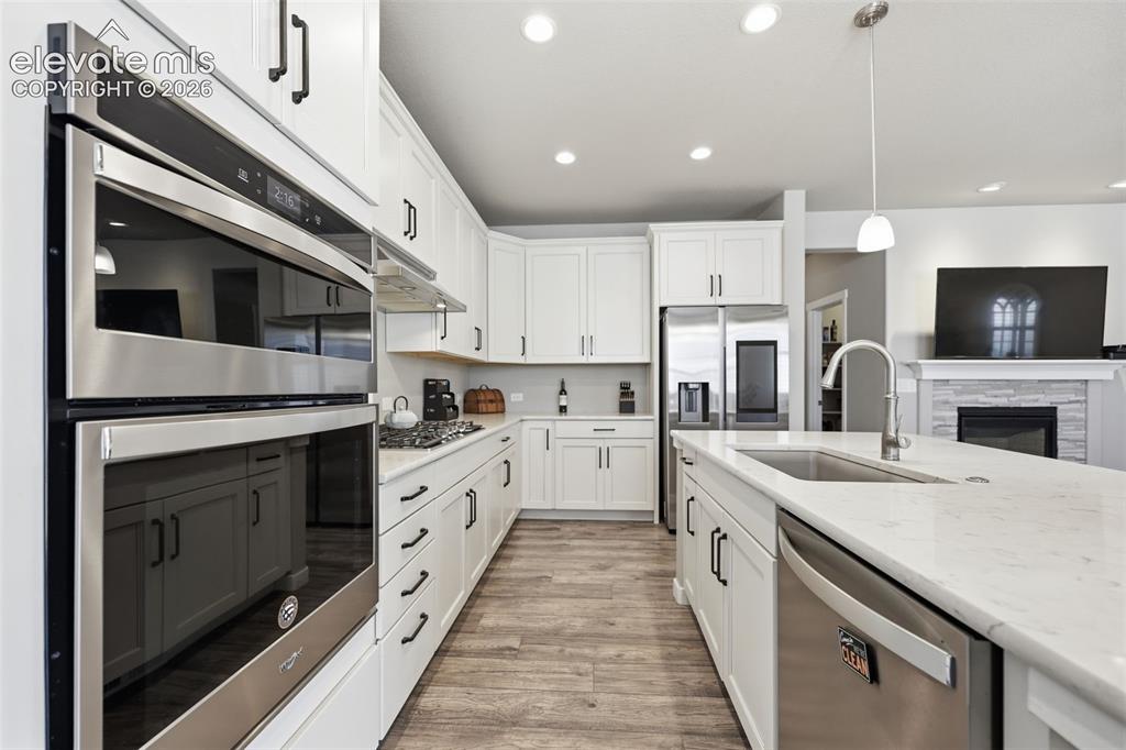Image 8 of 43: Kitchen featuring white cabinetry, stainless steel appliances, light  brown