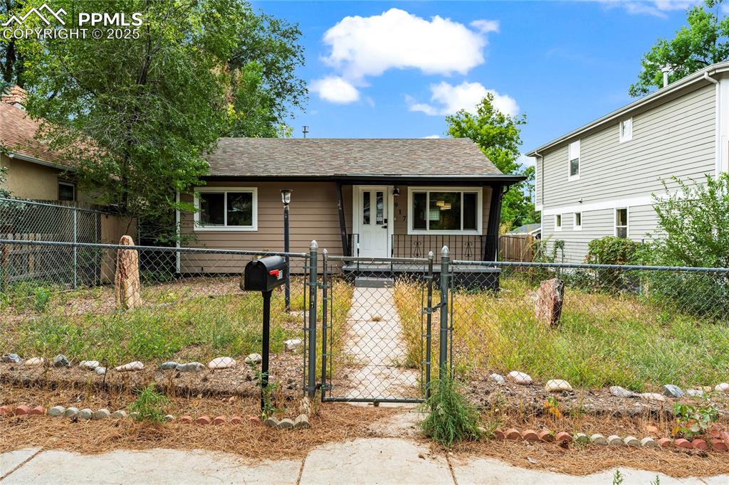 Caption: View of front of house featuring a gate, roof with shingles, and a fenced front yard