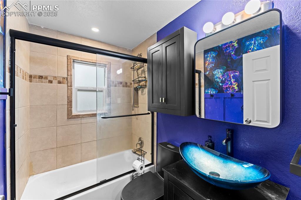 Image 17 of 26: Full bathroom with bath / shower combo with glass door, a textured wall, an