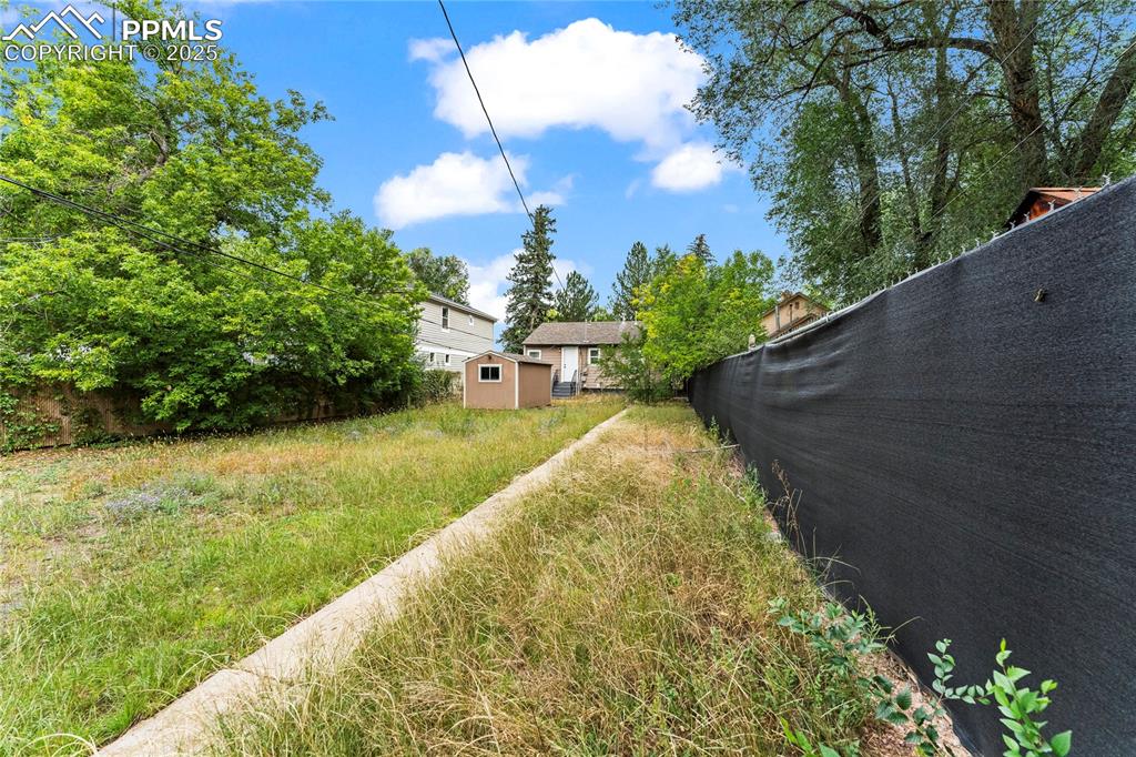 Image 20 of 26: Fenced backyard with a storage unit