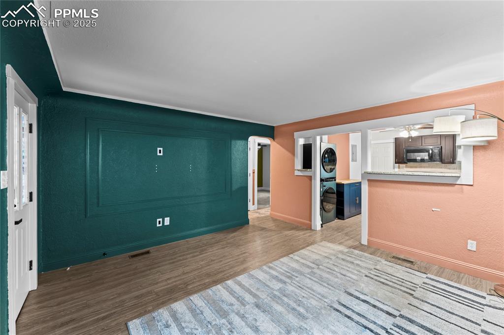 Image 5 of 26: Unfurnished living room featuring wood finished floors, stacked washing mac