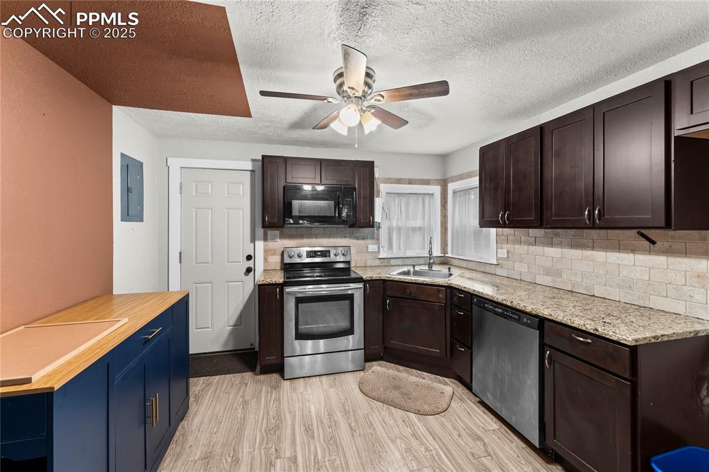 Image 7 of 26: Kitchen featuring dark brown cabinetry, light wood-style flooring, stainles