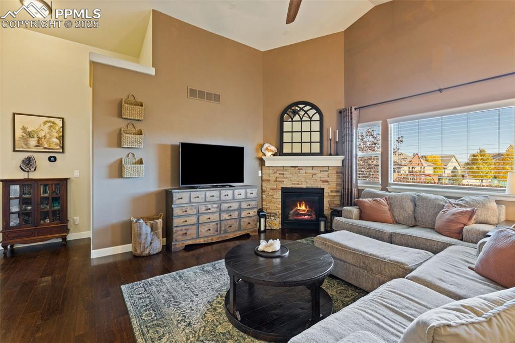 Image 10 of 31: Living area featuring dark wood-type flooring, a ceiling fan, a fireplace,