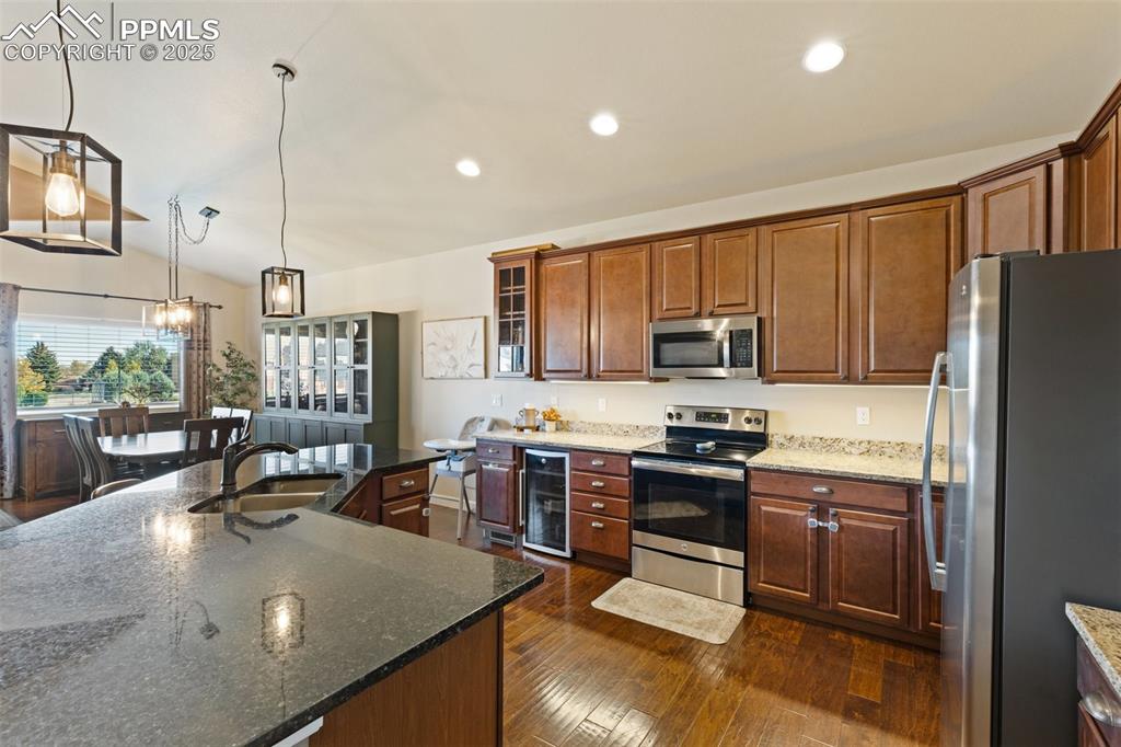Image 12 of 31: Kitchen featuring stainless steel appliances, dark stone countertops, hangi