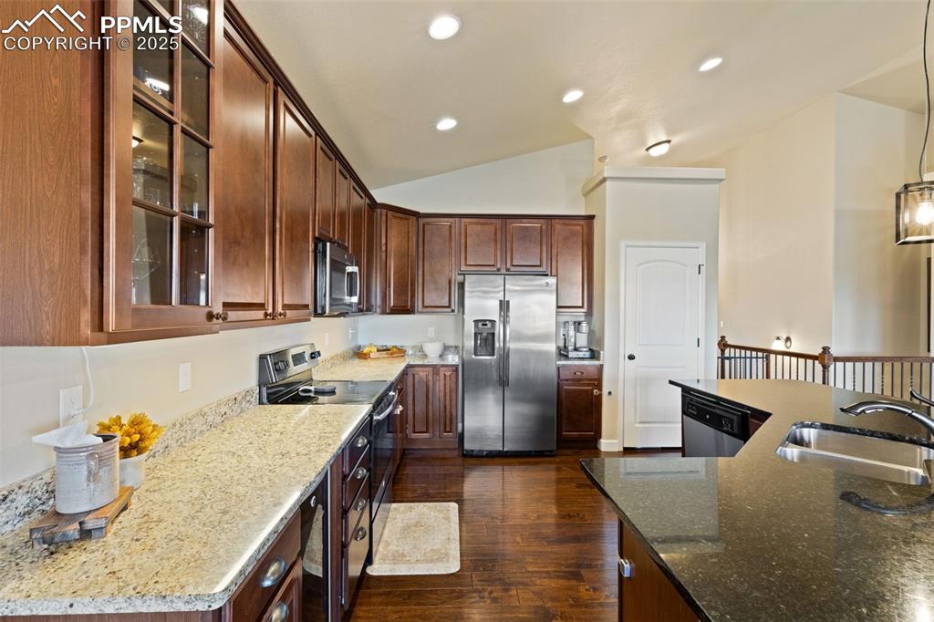 Image 13 of 31: Kitchen with glass insert cabinets, stainless steel appliances, dark stone