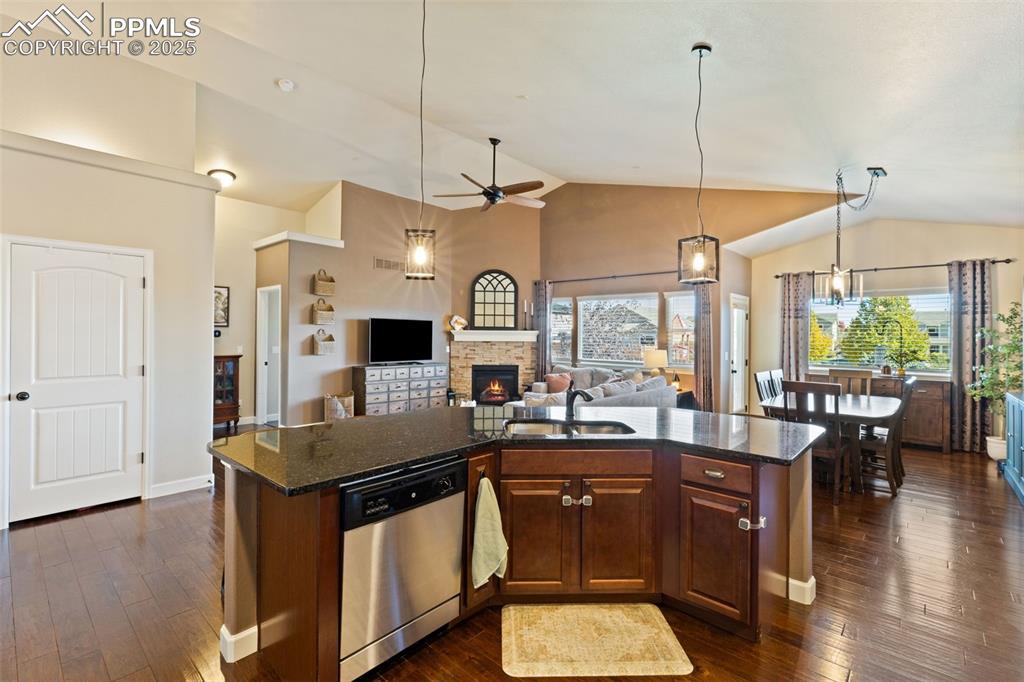 Image 14 of 31: Kitchen with a fireplace, dark stone countertops, dark wood-type flooring,