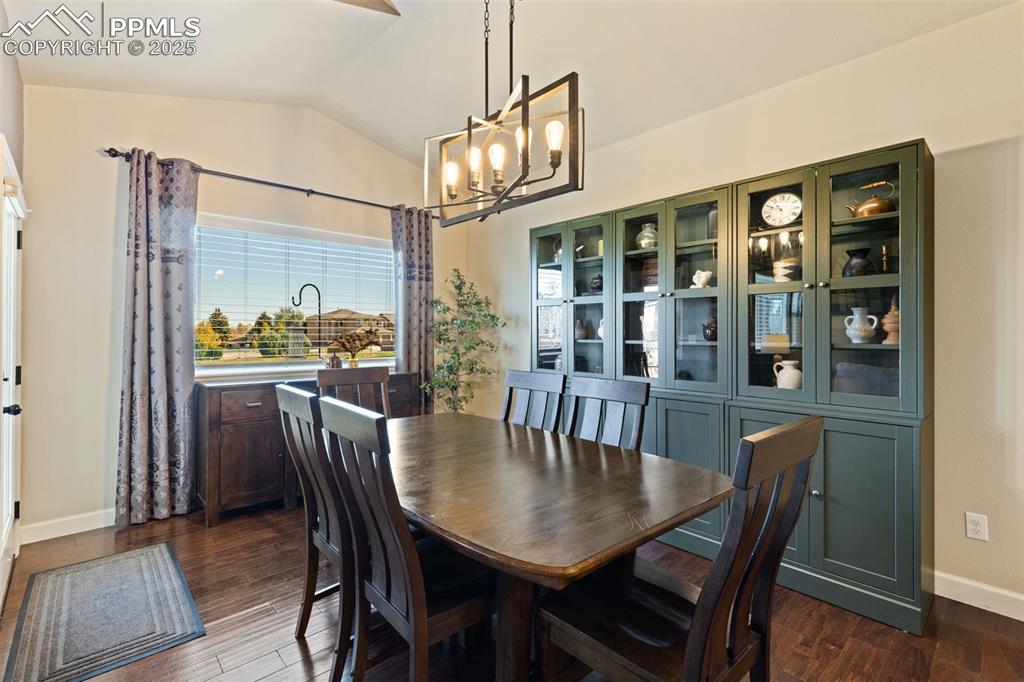 Image 15 of 31: Dining space featuring vaulted ceiling, a chandelier, and dark wood finishe
