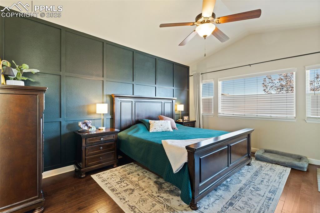 Image 16 of 31: Bedroom with a decorative wall, a ceiling fan, lofted ceiling, and dark woo