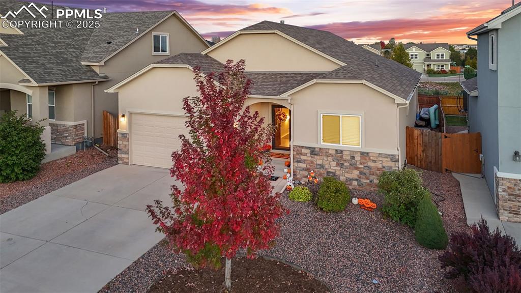 Image 2 of 31: View of front of home with stone siding, a shingled roof, stucco siding, dr