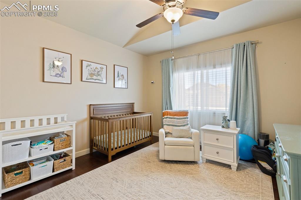 Image 21 of 31: Bedroom featuring a nursery area, wood finished floors, and a ceiling fan