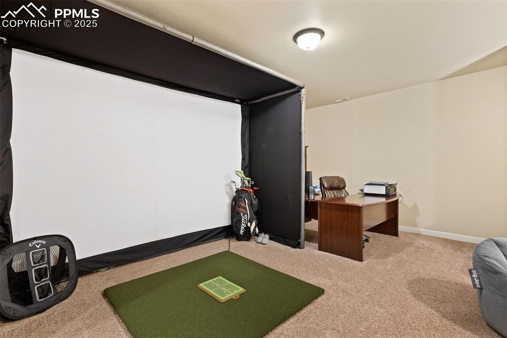 Image 25 of 31: Home office with golf simulator and light carpet