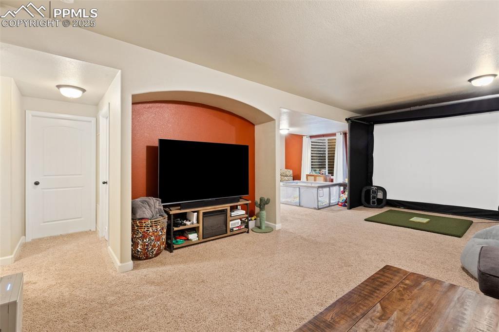 Image 27 of 31: Home theater featuring golf simulator and carpet floors