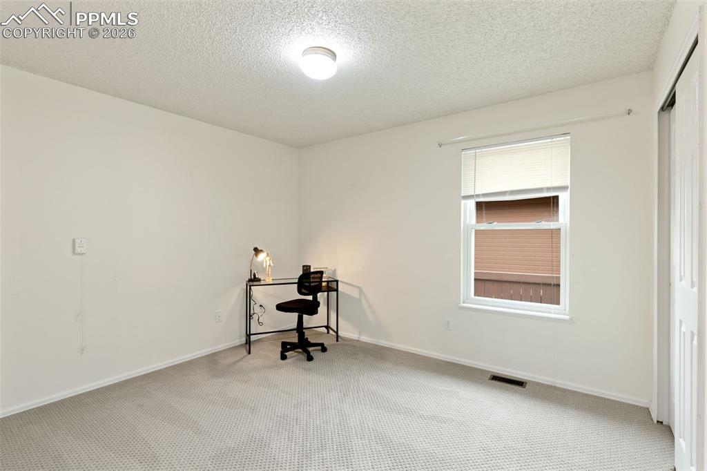 Image 10 of 20: The property features light-colored carpet flooring, a window with blinds, 