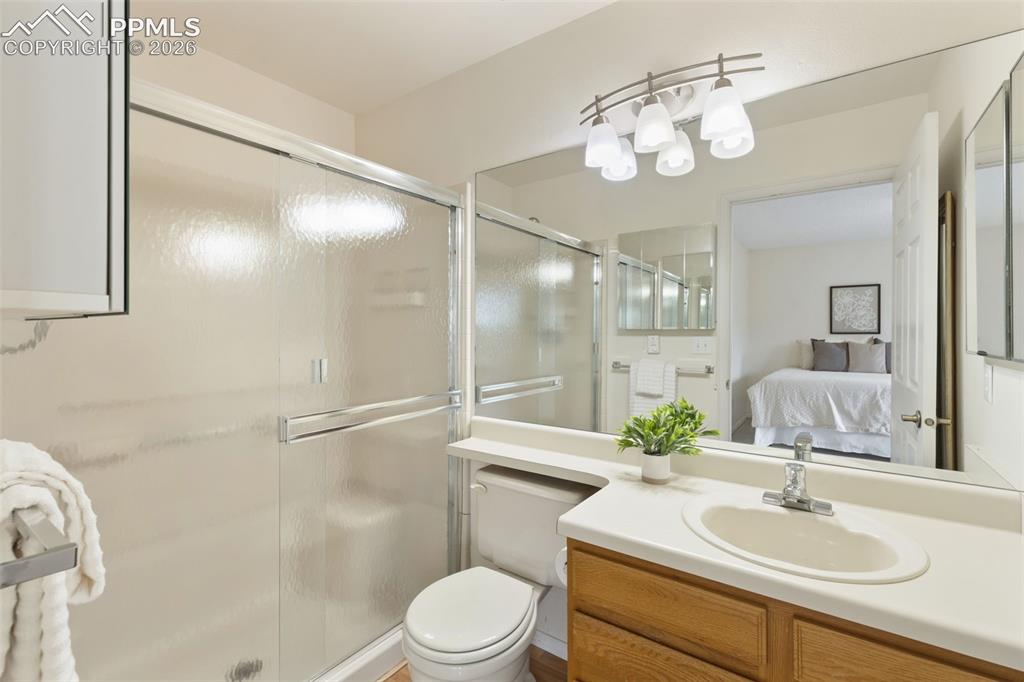 Image 13 of 27: Bathroom featuring a shower with sliding glass doors, a vanity with a light