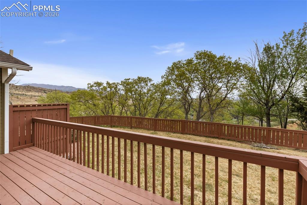 Image 14 of 27: The property features a spacious deck with a brown wooden railing and fenci