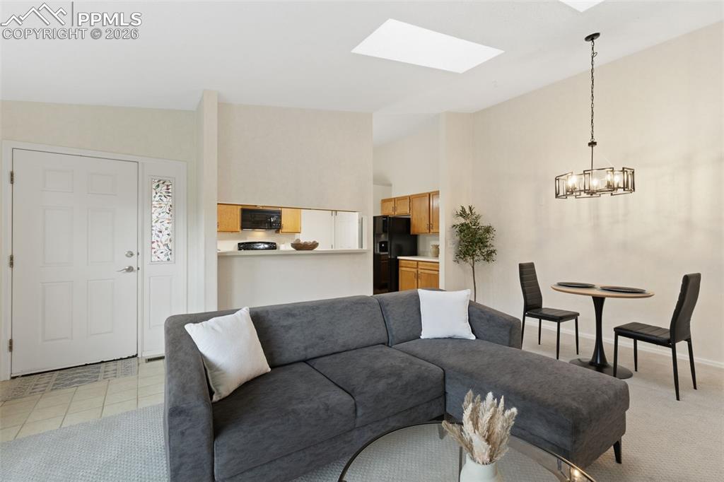 Image 2 of 27: Living area with vaulted ceilings, a skylight, and carpeted floors