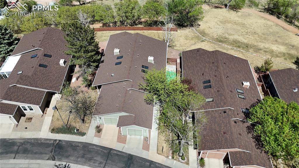 Image 20 of 27: The property features a brown shingle roof with skylights, surrounded by ma