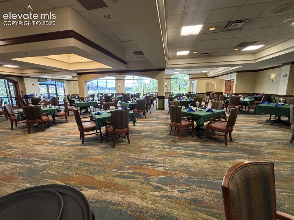 Image 21 of 27: Expansive dining area featuring a patterned carpet, large windows, recessed