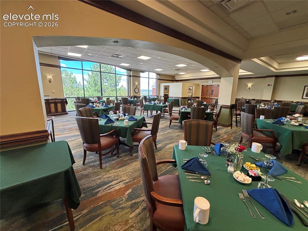 Image 22 of 27: Expansive dining area with large windows, patterned carpeting, and recessed