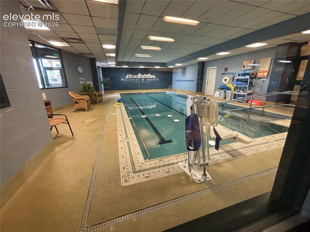 Image 27 of 27: Indoor swimming pool featuring an integrated hot tub and perimeter tile det