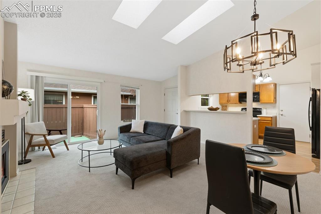 Image 3 of 20: Living area featuring light-colored carpeting, a fireplace with a tiled hea