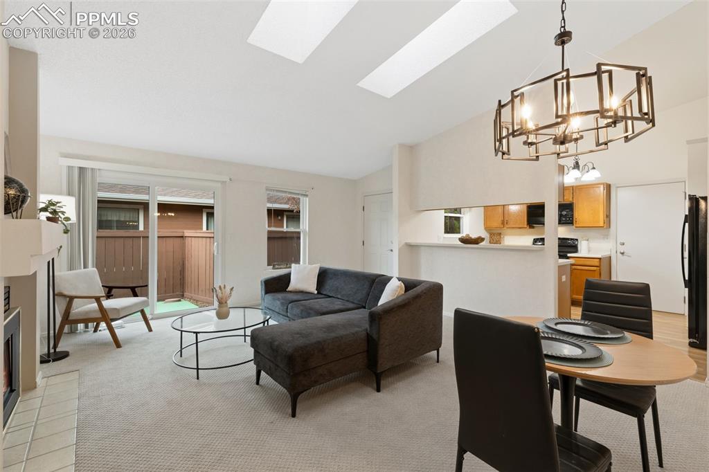 Image 3 of 27: Living area featuring light-colored carpeting, a fireplace with a tiled hea