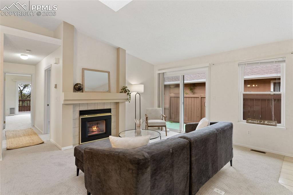 Image 6 of 27: This living area features a fireplace with a mantel, light-colored carpetin