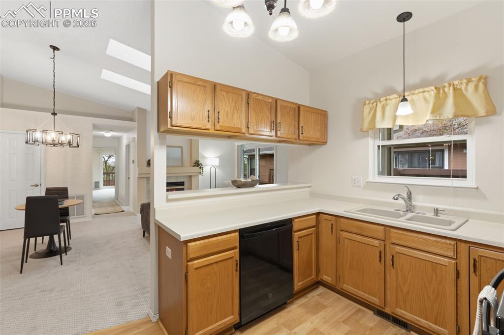 Image 7 of 27: The kitchen features wood cabinetry, a double basin sink, and a dishwasher