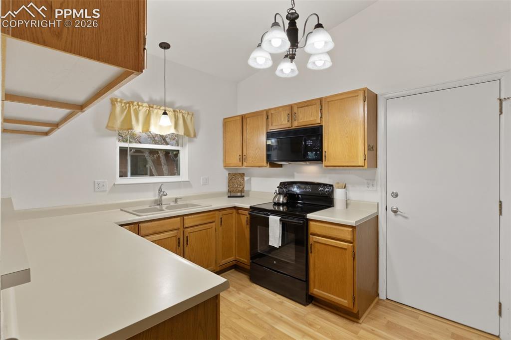 Image 8 of 27: Kitchen features wood cabinetry, light-colored countertops, a double-basin