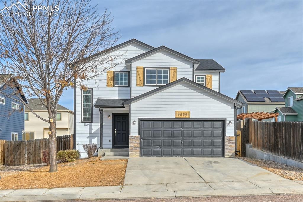 Caption: Traditional-style home with stone siding, concrete driveway, and a garage
