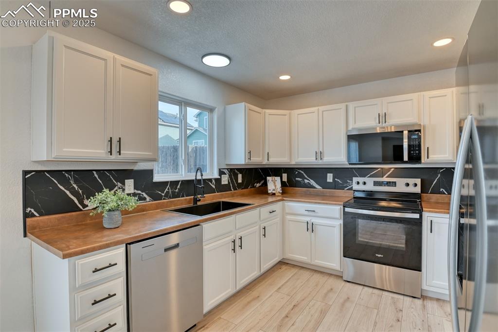 Image 11 of 45: Kitchen featuring stainless steel appliances, decorative backsplash, white