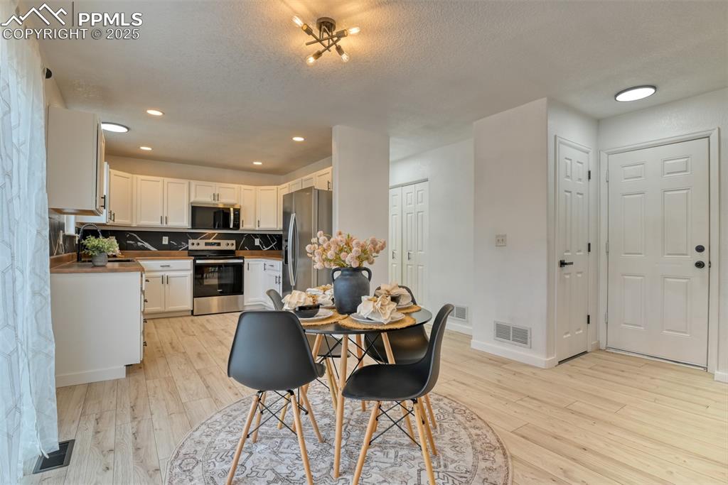 Image 13 of 45: Dining room with recessed lighting, light wood-style flooring, and a textur