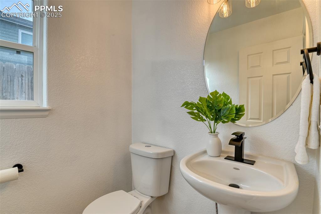 Image 14 of 45: Half bath with a textured wall and plenty of natural light