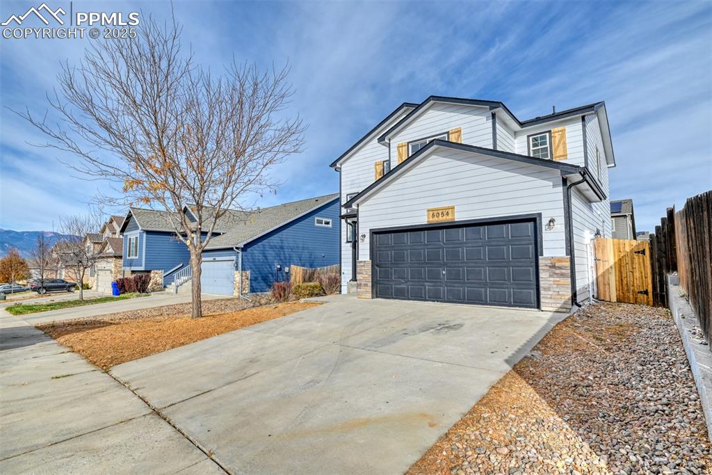 Image 2 of 45: View of front facade featuring a garage, concrete driveway, and stone sidin