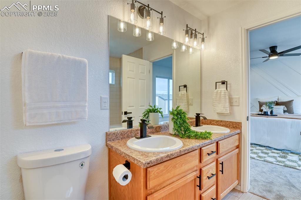 Image 23 of 45: Ensuite bathroom with a textured wall, double vanity, and ceiling fan