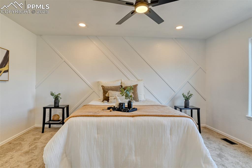 Image 25 of 45: Bedroom with light colored carpet, ceiling fan, recessed lighting, and a de