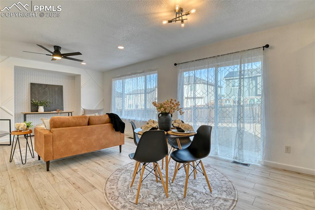Image 8 of 45: Dining area with a textured ceiling, light wood-style floors, and ceiling f