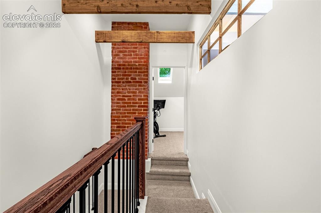 Image 29 of 49: Upstairs hallway with exposed beams and vintage window