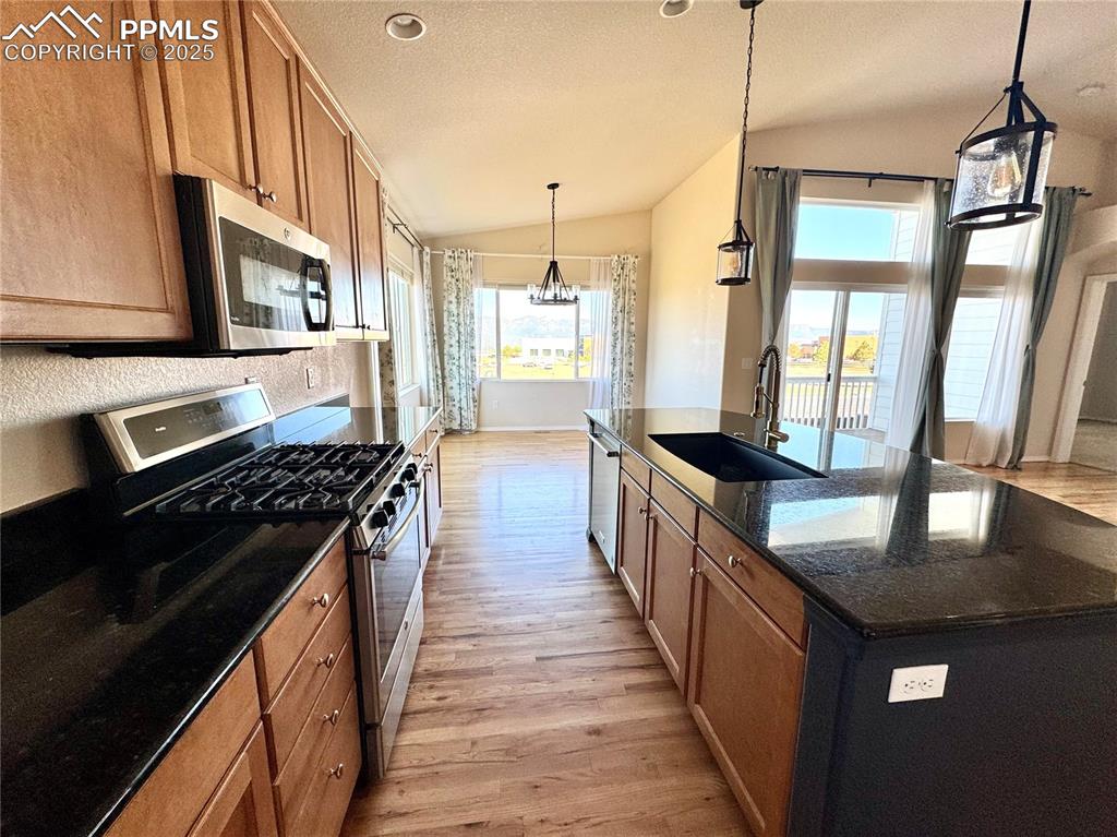 Image 13 of 36: Kitchen with stainless steel appliances, vaulted ceiling, light wood-style 
